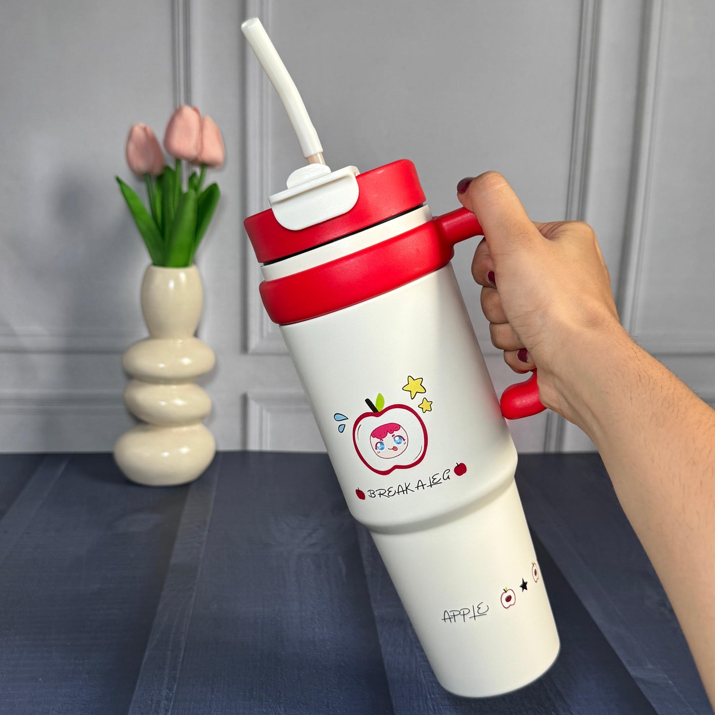 White tumbler with red lid and apple cartoon character print with straw and lid