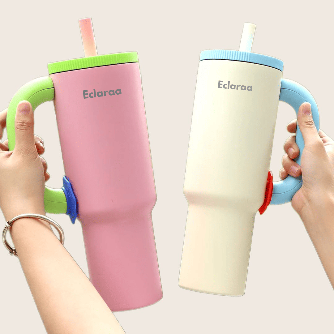 Two colorful cups with handles and straws, held by hands against a light pink background. Brand 'Eclaraa' visible on cups.